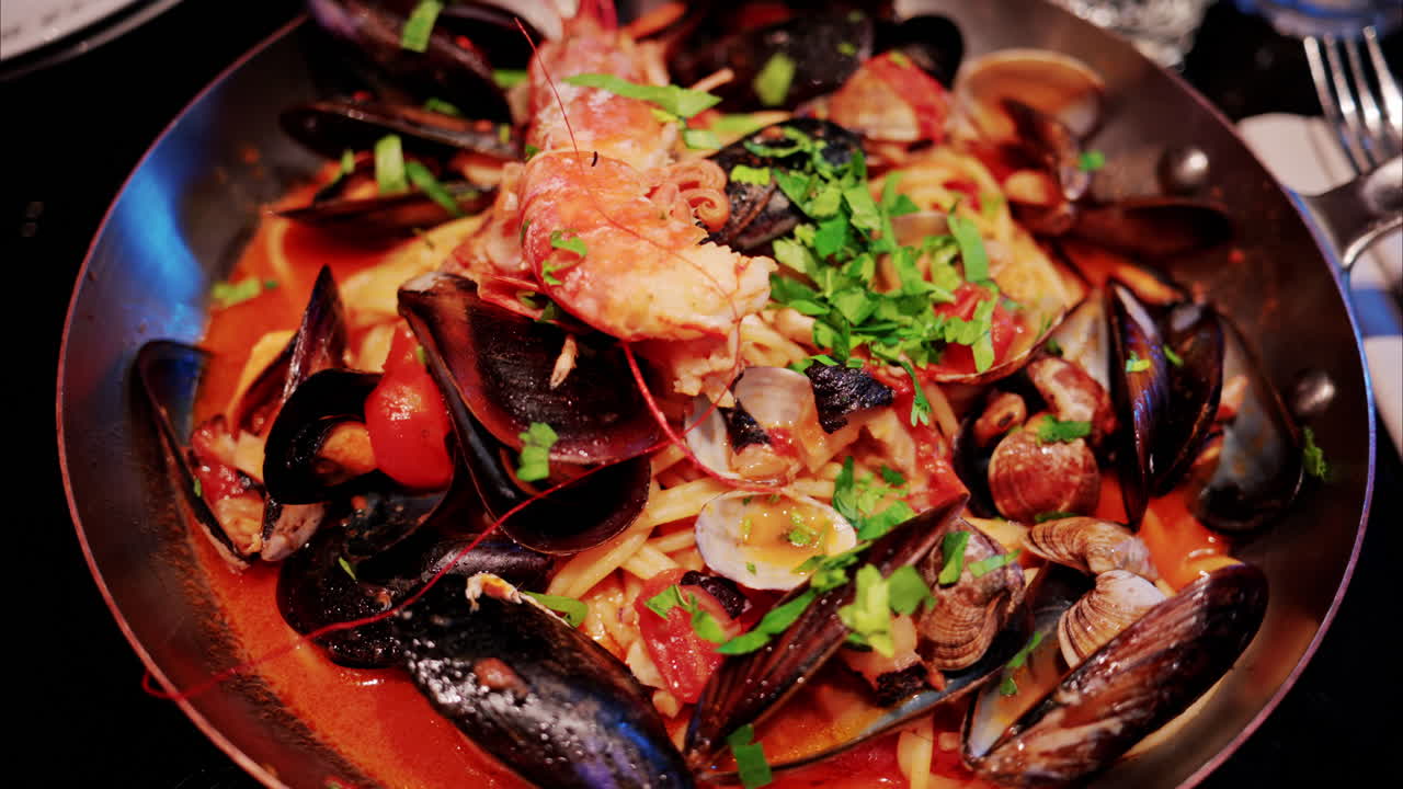 Close up of pasta with tomato sauce and mussels in a pan