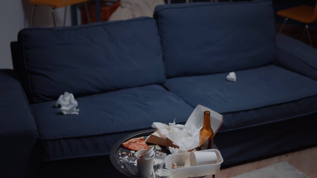 Chaos in empty living room with food garbage on table