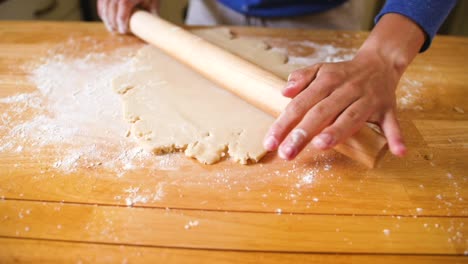 Hands-rolling-dough-with-rolling-pin-on-floured-surface
