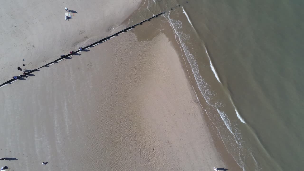 관광객들이 아래를 걷고 있는 황금빛 모래사장을 내려다보는 화창한 공중 회전 전망