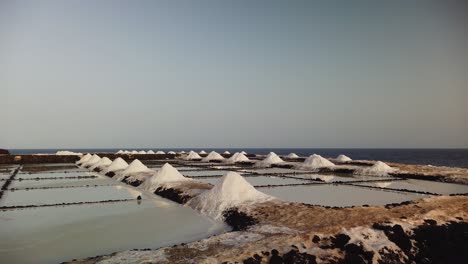 a lateral shot moving at ground level along a saltwork near the sea under a blue sky