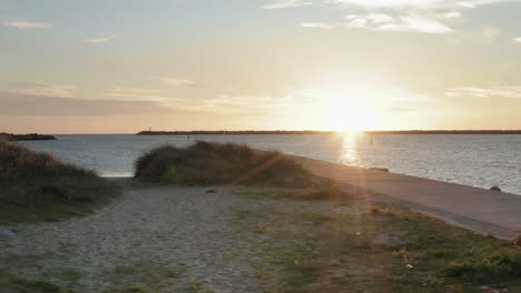 Shoreline-and-pier-next-to-Lima-river-estuary-flowing-into-Praia-do-Cabedelo-coast-at-sunset---Aerial-Low-angle-slide-tracking-shot