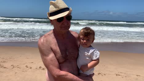 grandfather holding baby infant grandson at the beach