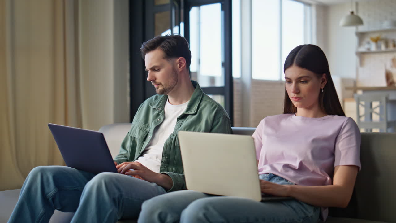 Focused couple working laptops at room interior closeup. Spouses cooperating