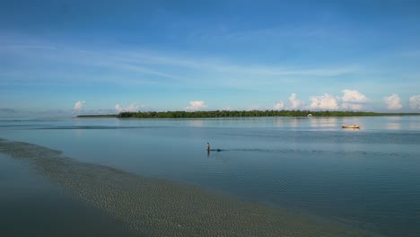 pescador local caminando en aguas poco profundas a baja