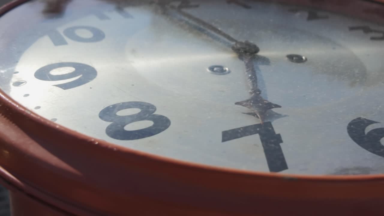 Primo piano medio ad arco di un vecchio quadrante d'orologio in piena luce solare con angolazione olandese, bloccato sul numero 7.