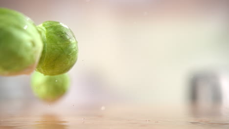 brussel spouts falling onto the wooden table, bouncing and splashing water droplets around the kitchen in macro and slow motion
