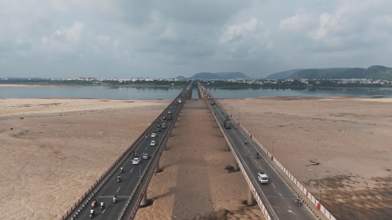 This aerial video captures the city's vibrant urban landscape, where the majestic Krishna River gracefully winds its way through the landscape, intersecting the Chennai-Kolkata Highway bridge
