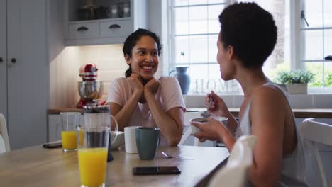 Mixed-race-lesbian-couple-preparing-and-eating-breakfast-in-kitchen