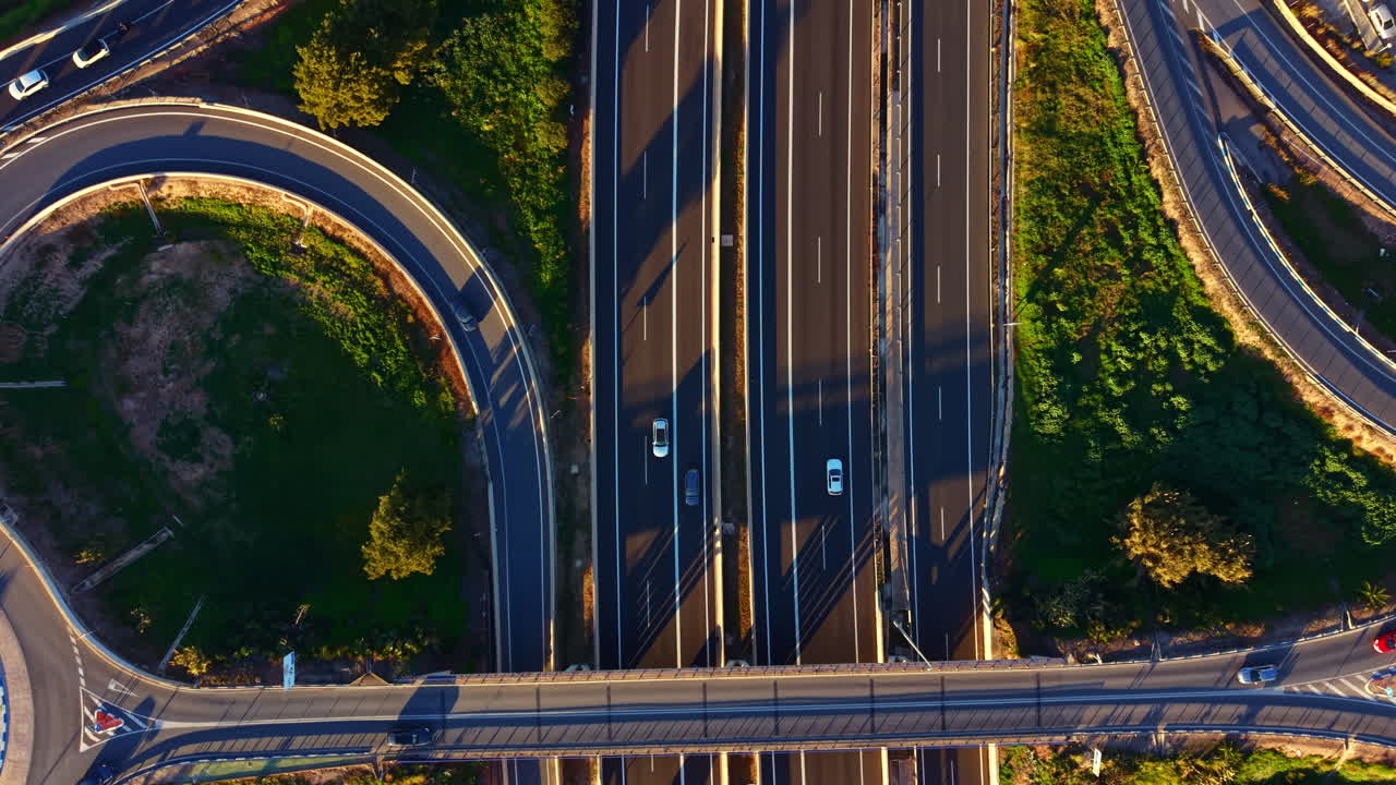 Traffic flows on highways and roads in a city during the day with cars moving in different directions at a junction