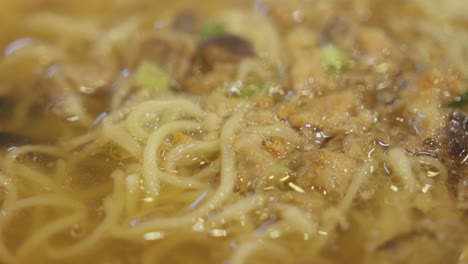 chopsticks inside asian bakmi noodle soup. close up