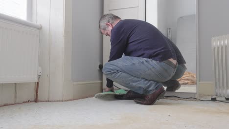 Man-removing-underlay-from-room-floor