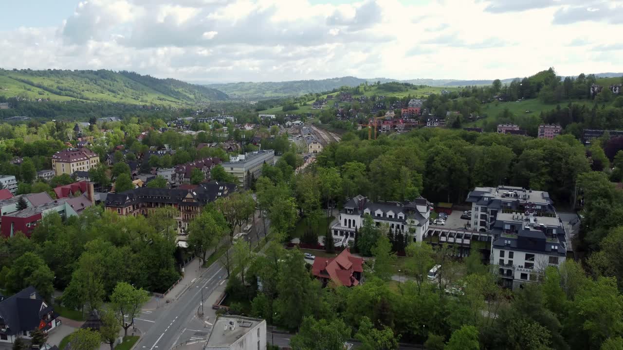 Flyover of Zakopane, Poland, a resort town village with traditional Goral architecture near the Polish Tatra mountains, farmland, forests, valley, flying North from Poland's border 4K Tracking Forward