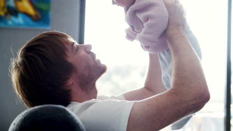 padre feliz sosteniendo a la hija bebé en el aire
