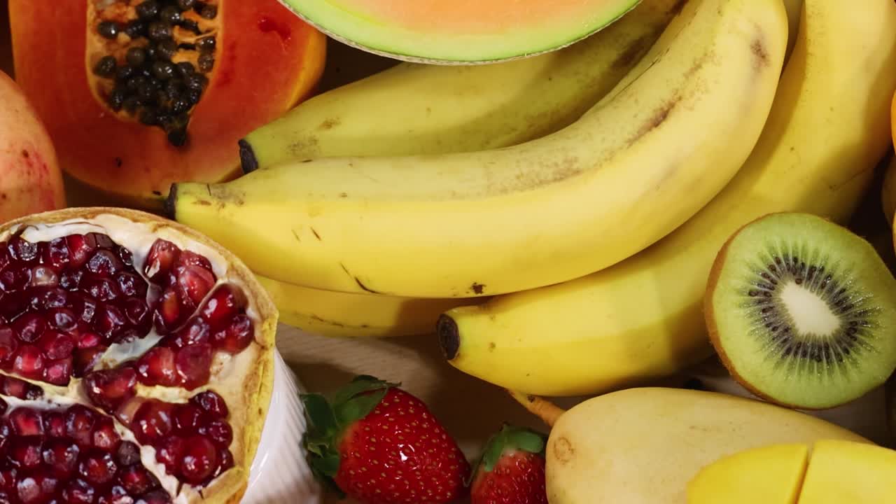 Et fargerikt utvalg av bananer, mango, papaya og annen fersk frukt i en levende utstilling.