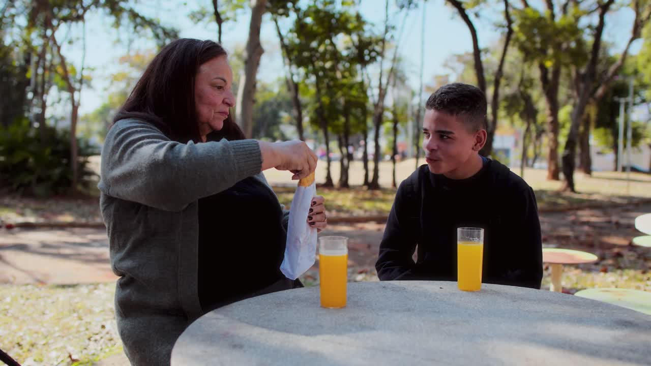Dos personas disfrutando de un aperitivo y zumo en un parque