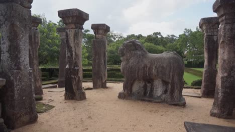 large carved stone statue surrounded by tall stone pillars on temple grounds