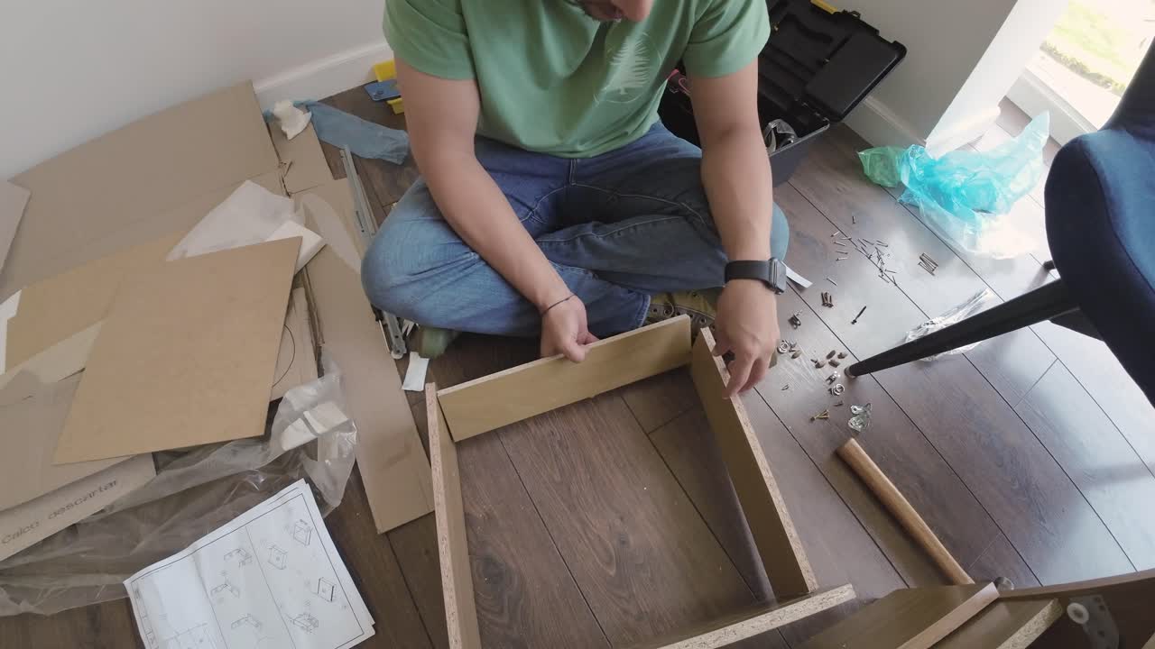 Uomo che monta mobili in kit su un pavimento di legno