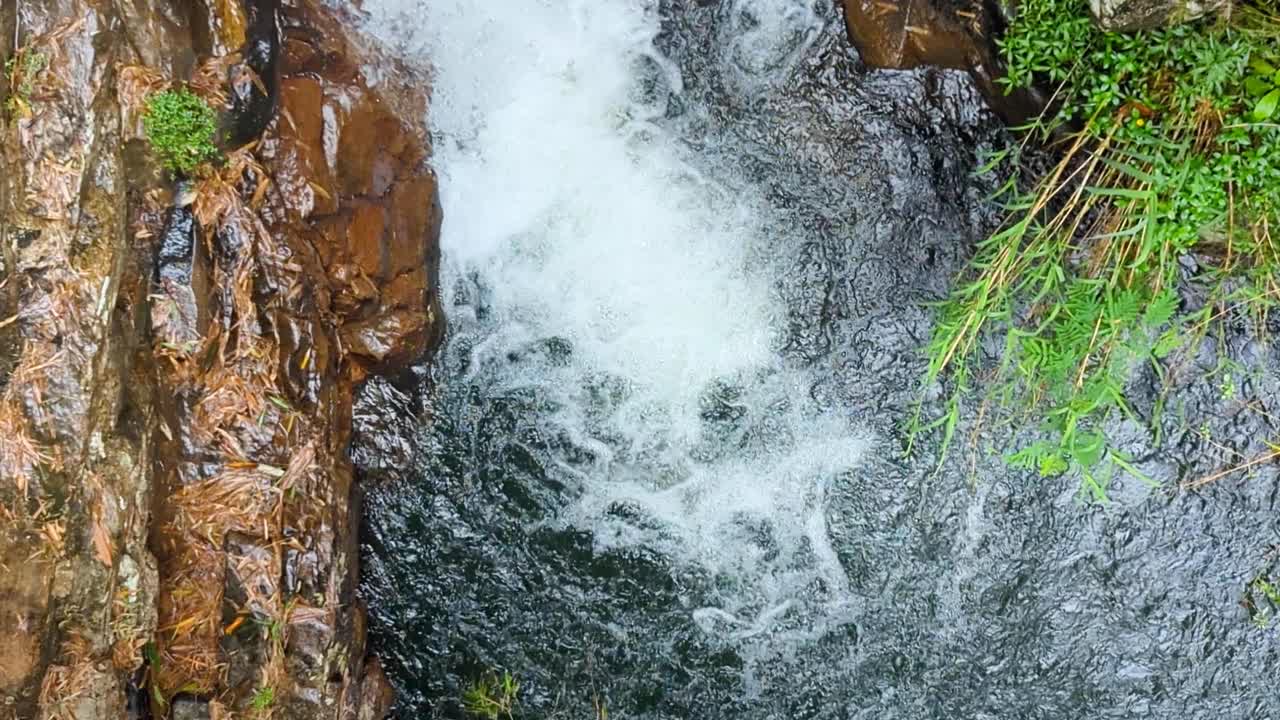Aerial view of frothy whitewater of Kadiyanlena falls waterfall and Mahaweli river with natural swimming hole in Kandy district of Sri Lanka