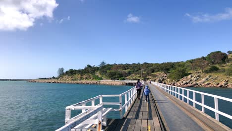 mother and daughter walking across a bridge with white railings