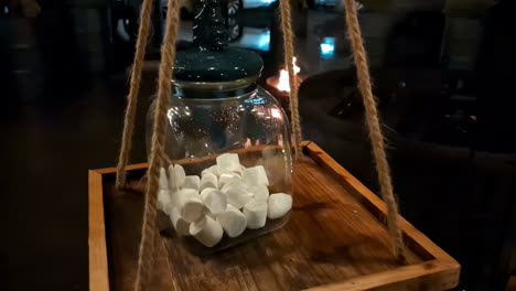 close-up panning view of a jar with marshmallows on a wooden plate