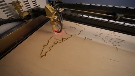 cnc laser cutting machine cuts world map on wooden plank and plywood