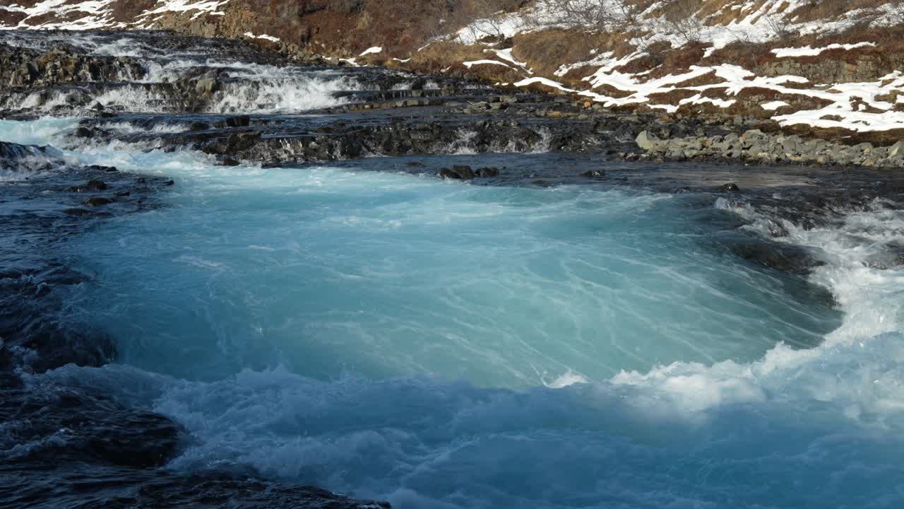 Brúarfoss in Haukadalur, Iceland, displays its signature icy-blue water rushing through volcanic rocks.