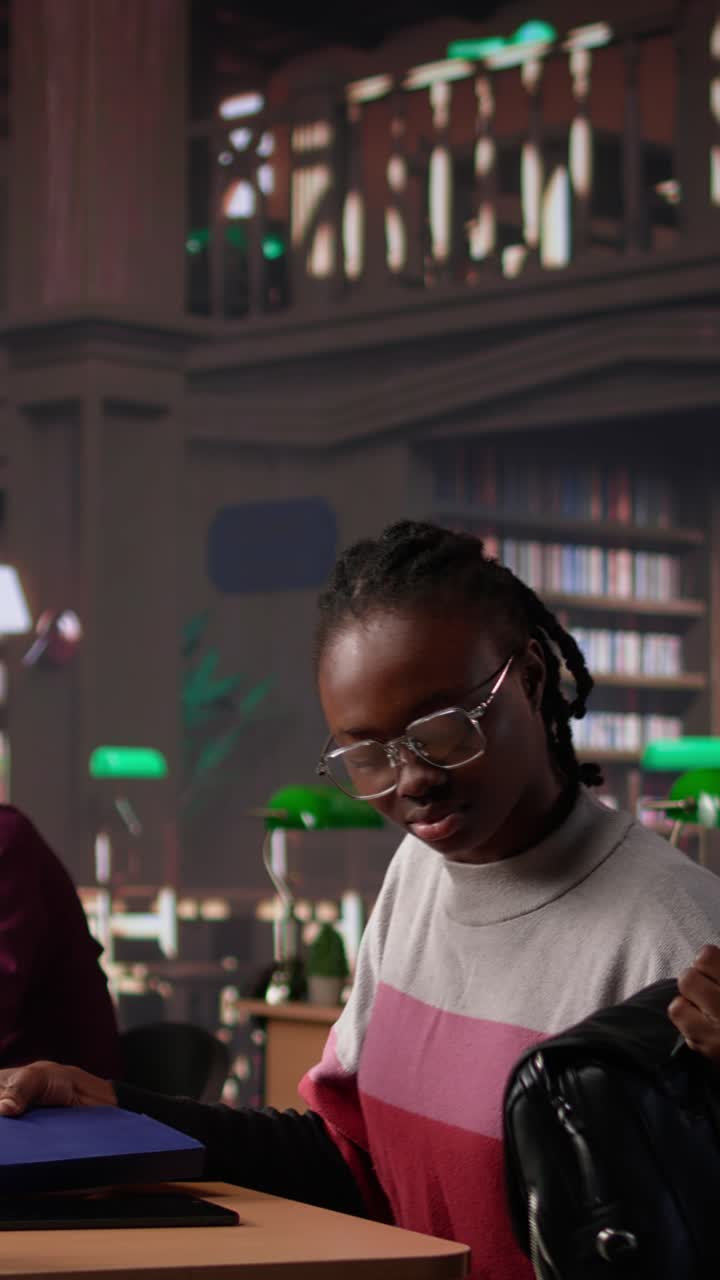 Vertical video african american student comparing class notes with data from the library