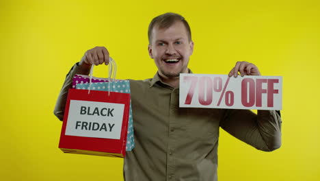 man showing up to 70 percent off inscription and shopping bags, looking satisfied with low prices