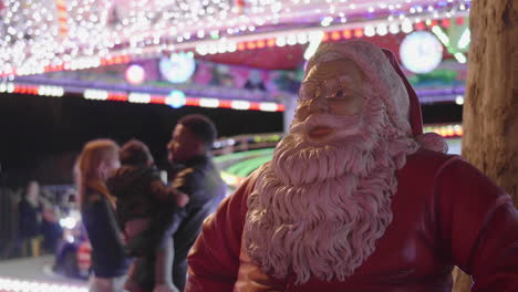 santa claus statue with a young couple with a child in background. christmas