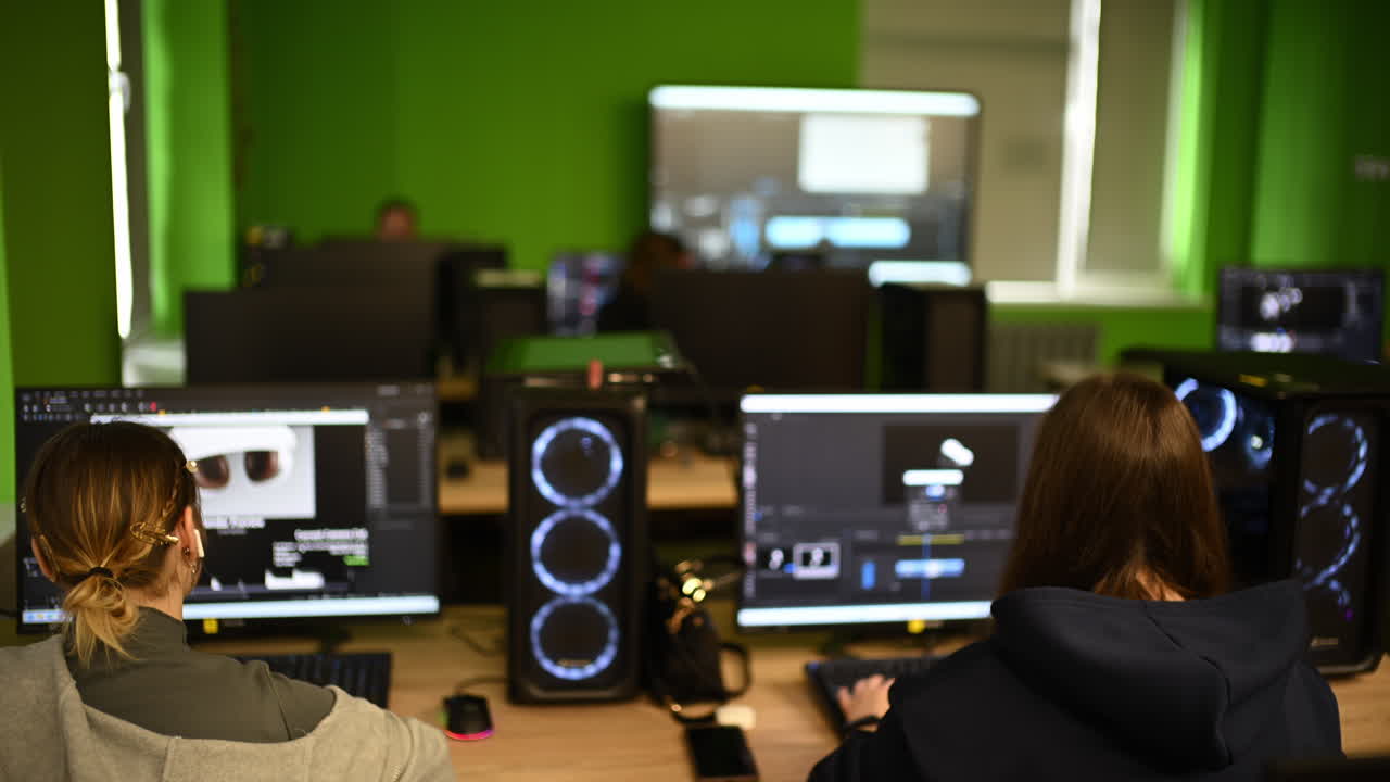 Modern computer classroom with multiple workstations, screens and students working