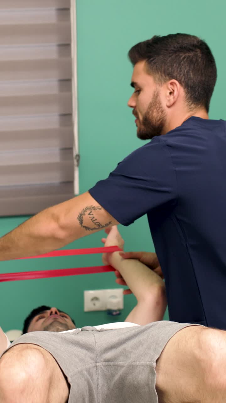 Fisioterapeuta Orienta Paciente Masculino em Exercícios com Faixa de Resistência