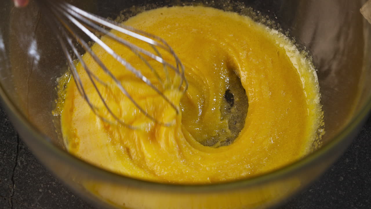 Hands adding sugar while stirring a pastry dough. Slow motion