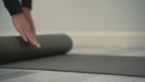 young woman unrolls yoga mat on floor and prepares to meditate and do exercises. close-up.