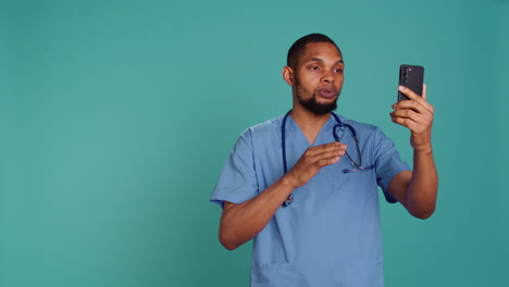 Nurse-waving-hand-in-videocall-meeting-using-phone,-saluting-patient