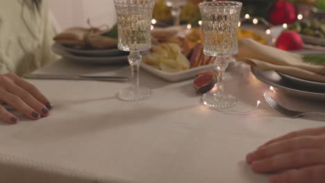 Nahaufnahme-Eines-Nicht-Erkennbaren-Paares,-Das-Beim-Weihnachtsessen-Am-Tisch-Händchen-Hält
