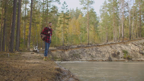 un hombre camina por un sendero en un parque cerca de un lago a primera hora de la mañana en el otoño. hombre en la cima de la colina. joven de pie en el muelle con los brazos extendidos. imágenes de alta calidad 4k