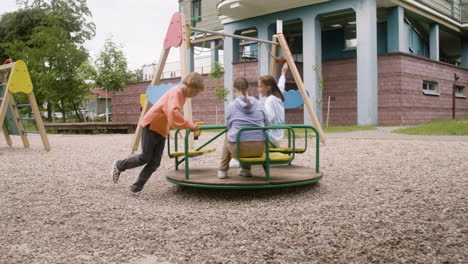 Little-girl-with-down-syndrome-playing-with-her-friends-in-the-park-on-a-windy-day.-They-are-spinning-on-a-carousel