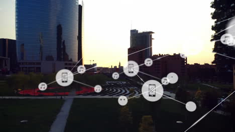 animation of icons connected with lines over aerial view of garden and business park against sky