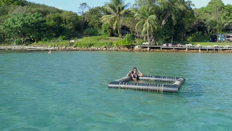 Modelo-Sentado-Y-Saludando-En-Un-Dispositivo-Flotante-En-El-Océano,-Koh-Kood,-Tailandia