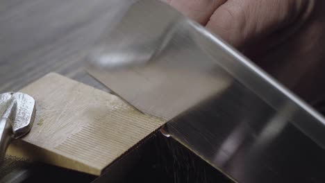 primer plano de las manos del hombre aserrando un detalle de madera con una sierra de mano. carpintero hace un peine de madera hecho a mano. cine 4k video