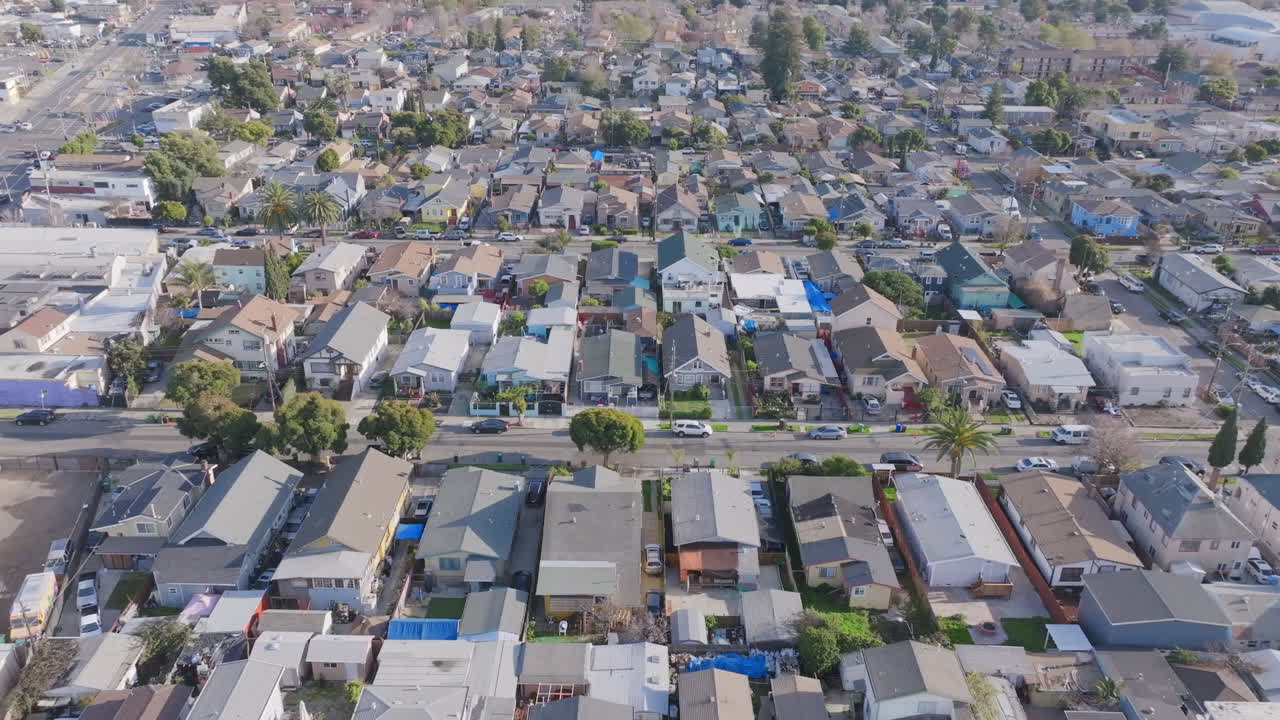 Aerial drone footage birds eye view flying over streets and rows of homes south of Oakland, CA.