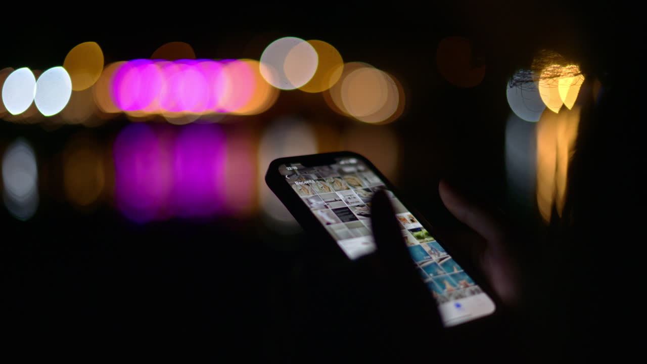 Woman looking at pictures on her phone on the beach at night
