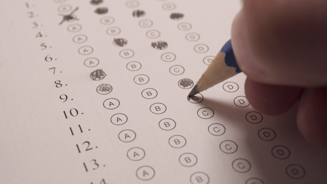 la mano usa un lápiz para sombrear la letra c en la hoja de respuestas