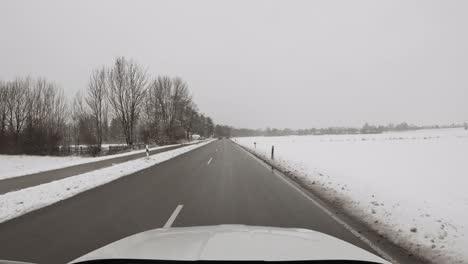 Mit-Dem-Auto-Durch-Eine-Winterlandschaft-In-Ländlicher-Atmosphäre-Fahren,-Während-Etwas-Schneit