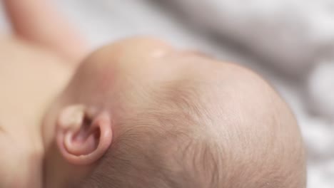 Caucasian-Newborn-Baby-Lying-On-Its-Back-Naked-In-Bedroom