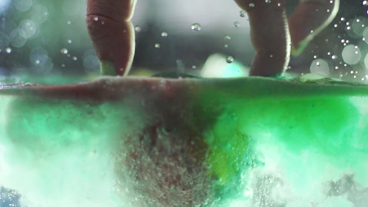 toma en cámara lenta de una bomba de baño burbujeando en el agua, una perspectiva única donde se puede ver por encima y por debajo de la línea de agua