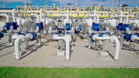 aerial tracking shot in front of pipes at a natural gas pumping station, sunny day