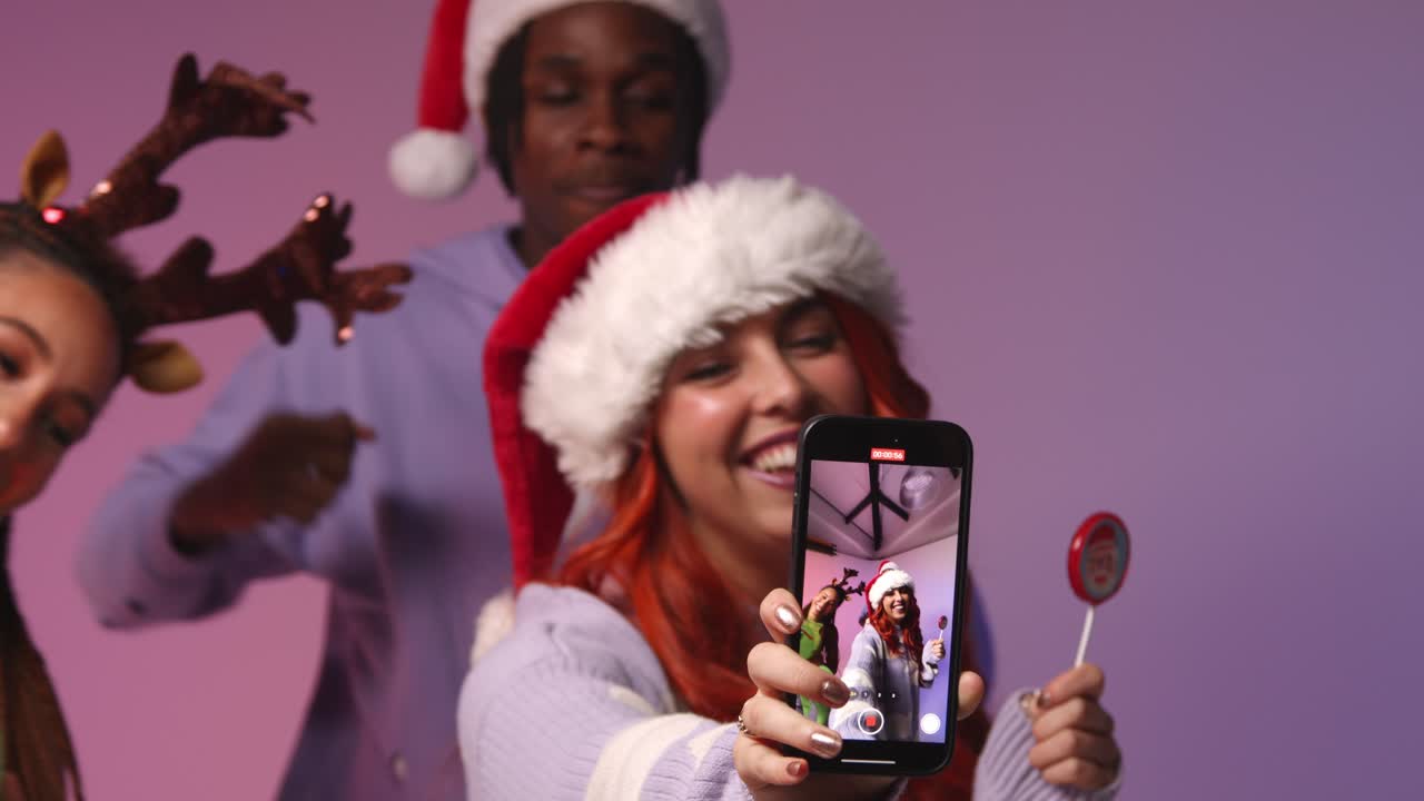 fotografía de estudio de amigos de la generación z bailando y posando para selfies en una fiesta de navidad con sombrero de papá noel y cuernos de reno