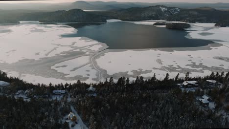lago brompton durante el invierno con agua congelada y estructuras cubiertas de nieve en quebec, canadá